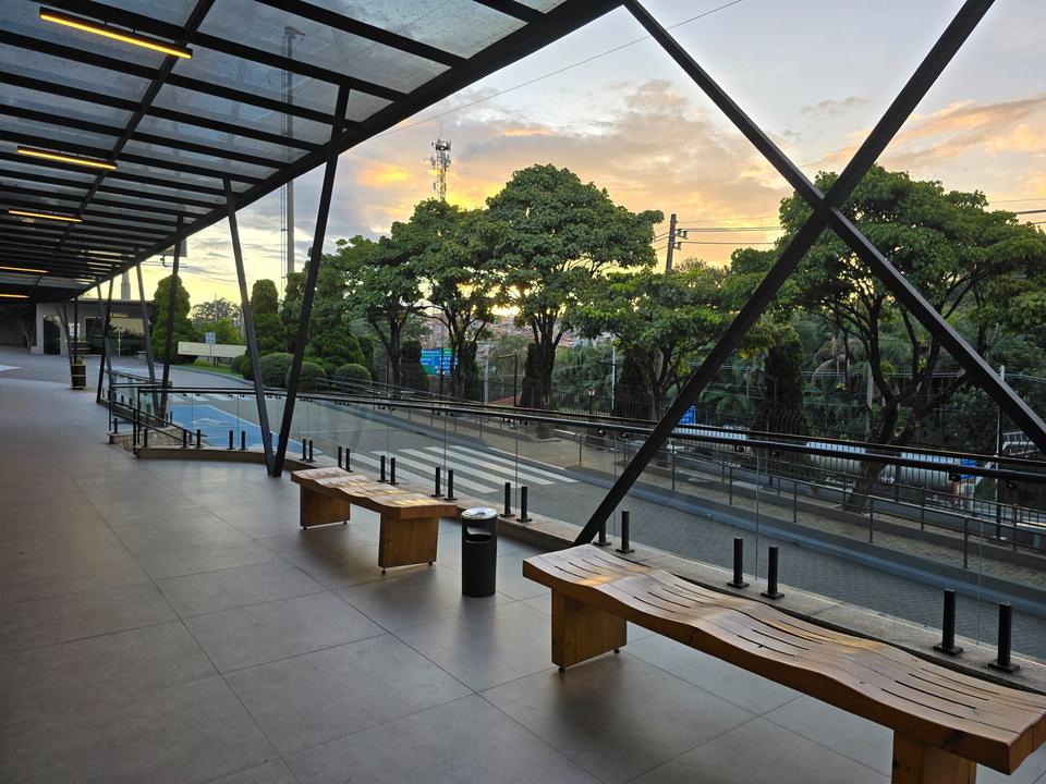Área coberta de convivência com bancos de madeira, no fim da tarde
